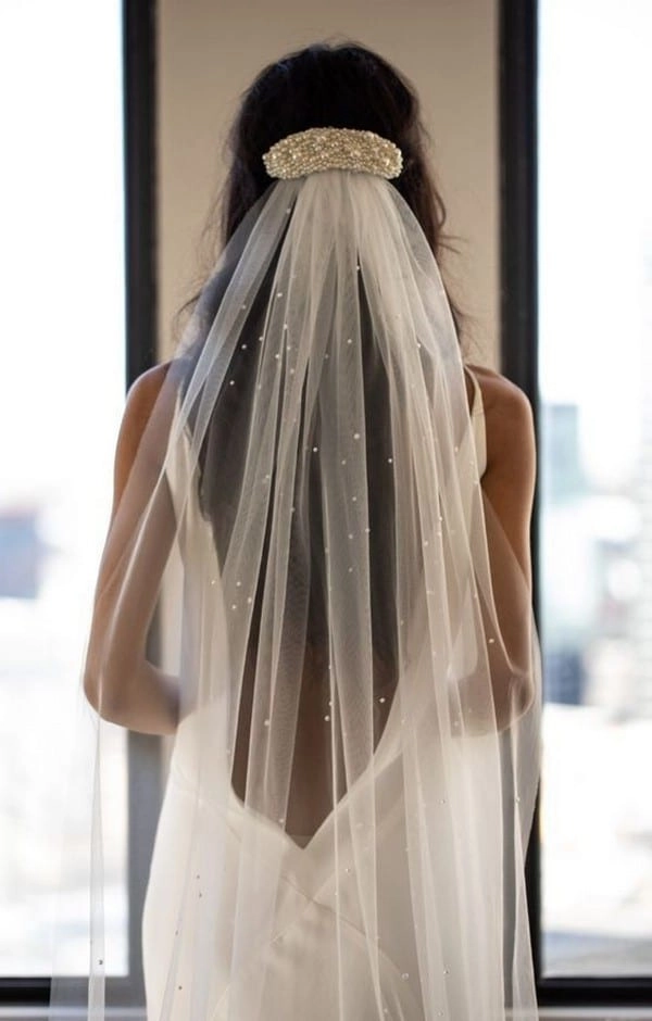 Elegant long wavy wedding hair adorned with a delicate veil in image 12 Bridal long wavy hair styled elegantly with a flowing veil