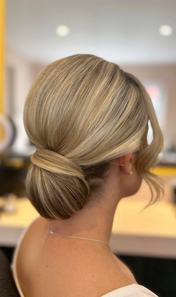 Elegant wedding hairstyle featuring a soft low bun and face framing strands for brides Bridal low bun hairstyle with delicate face framing pieces for a wedding look