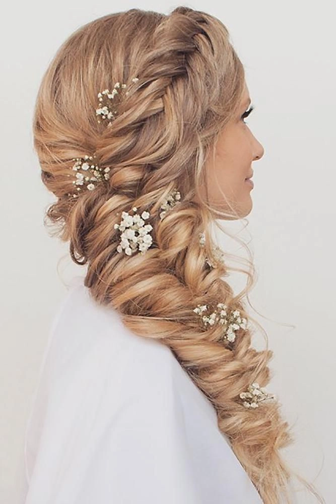 Beautiful wedding hairstyle featuring a side braid for the bride Elegant bridal hair with side braid adorned with delicate flowers
