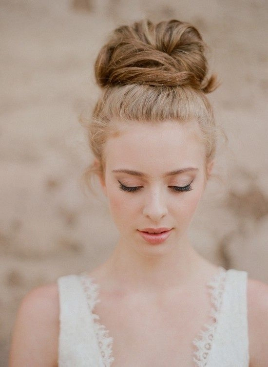 Wedding Hairstyles gallery featuring a chic bridal top knot bun style Bridal top knot bun hairstyle with elegant curls and floral accents
