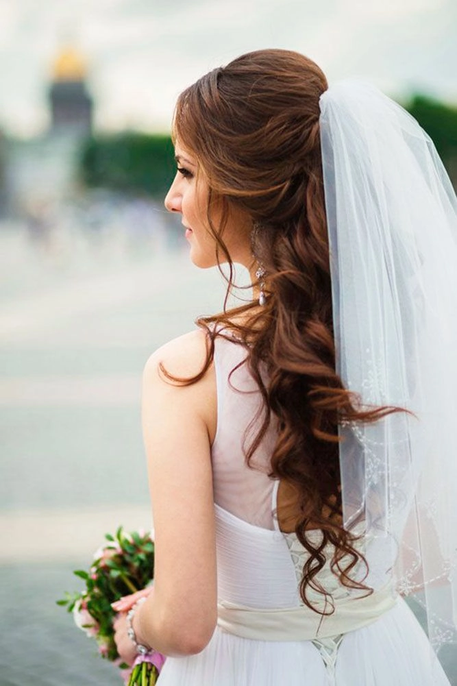 Elegant long wavy wedding hairstyle complemented by a sheer bridal veil on the big day Bride showcasing long wavy wedding hair styled beautifully under a delicate veil