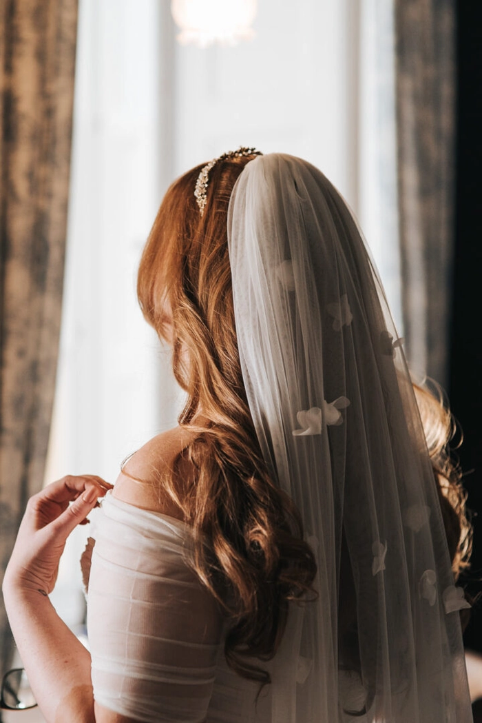 Elegant long wavy wedding hairstyle complemented by a flowing veil on the bride Bride with long wavy wedding hair styled elegantly, wearing a delicate veil