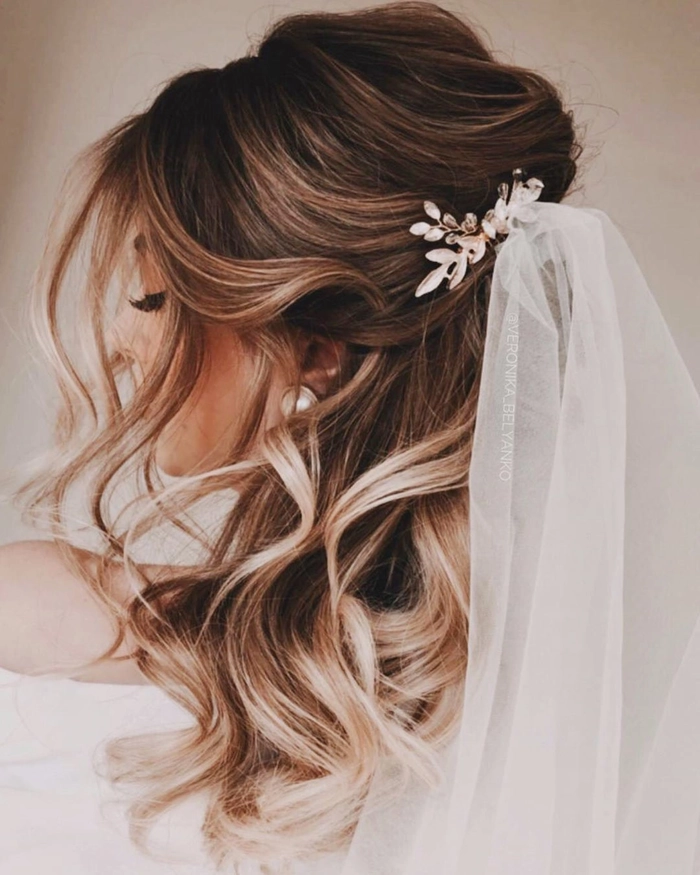Elegant long wavy wedding hairstyle complemented by a delicate bridal veil Bride with long wavy wedding hair styled elegantly under a flowing veil