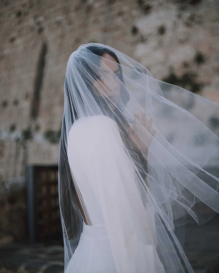 Elegant long wavy wedding hairstyle complemented by a flowing veil in photo 9 Bride with long wavy wedding hair styled elegantly under a delicate veil