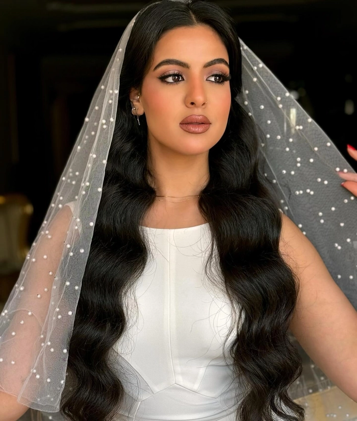 Elegant long wavy wedding hairstyle paired beautifully with a flowing veil Bride with long wavy wedding hair styled elegantly under a delicate veil