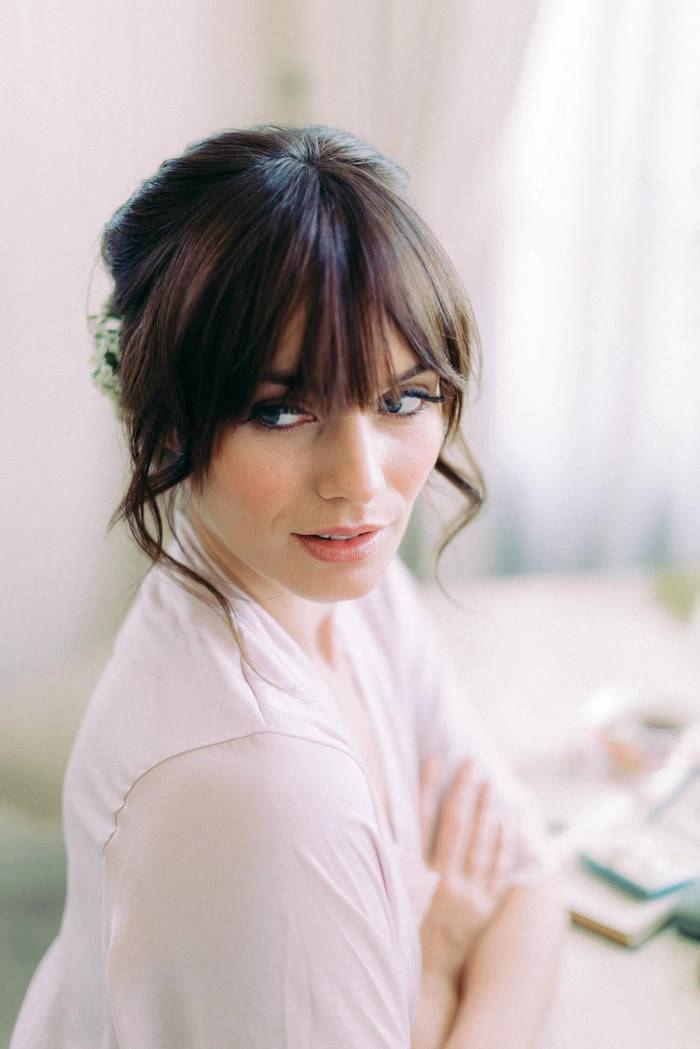Bride with elegant wedding hair with bangs styled in soft waves