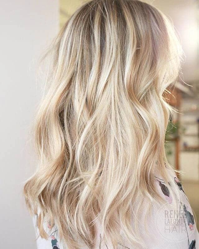 Elegant wedding hairstyle for blonde balayage with soft curls and floral accents