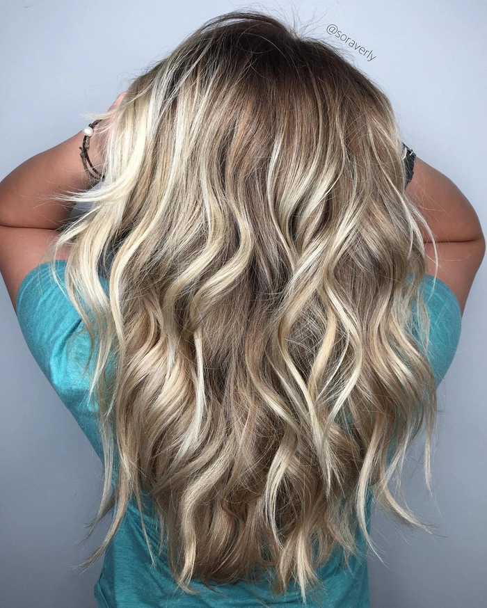 Elegant wedding hairstyle for blonde balayage featuring soft waves and floral accents