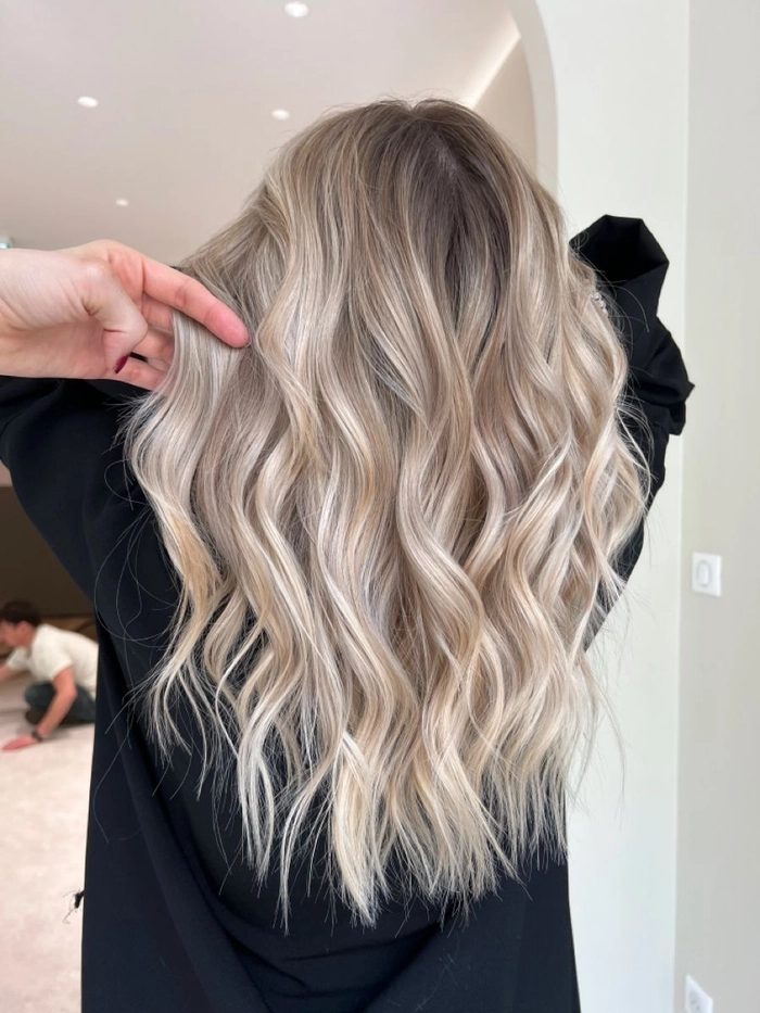 Elegant wedding hair styled for blonde balayage with soft waves and floral accents