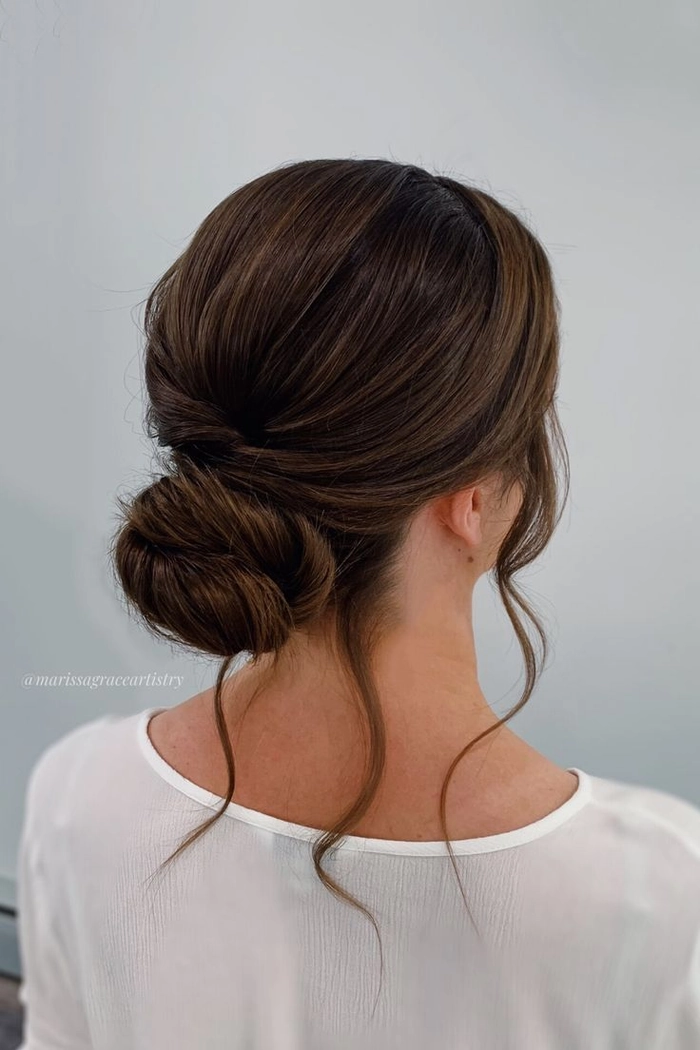 Soft and sophisticated wedding hairstyle featuring a low bun and gentle face framing strands Elegant bridal low bun with delicate face framing pieces for a romantic wedding look