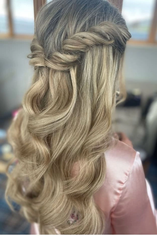 Beautiful wedding hairstyle showcasing a half up half down look for bridesmaids Elegant bridesmaid half up half down hairstyle with soft curls and floral accents