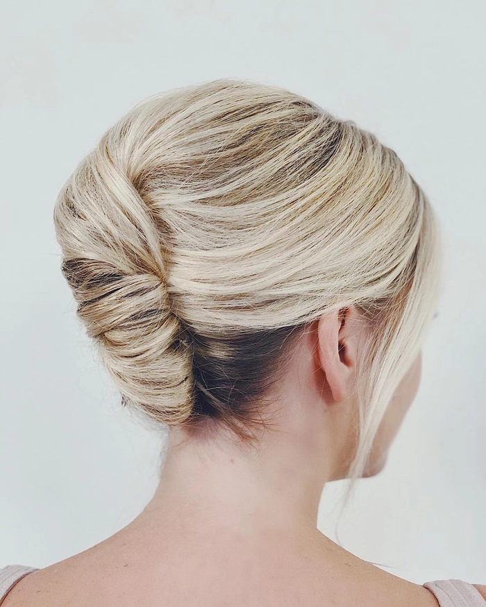 Elegant French twist bridal hair styled with soft curls and delicate accessories