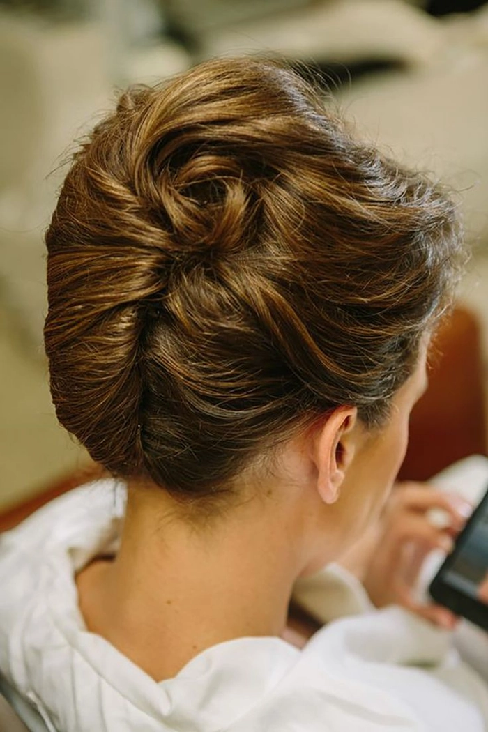 Elegant French twist bridal hair styled with soft curls and delicate accessories