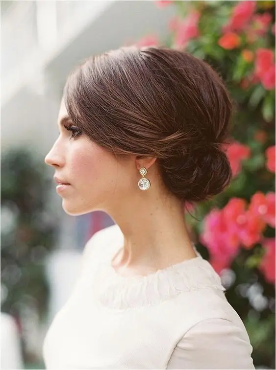 Chic and simple wedding hairstyle featuring a sleek minimalist bun Elegant modern minimalist bridal bun with delicate floral accents