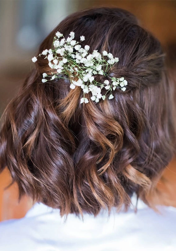 Short bob wedding hairstyles for brides with soft waves and minimalistic adornments Elegant short bob wedding hairstyle featuring delicate floral accessories for brides
