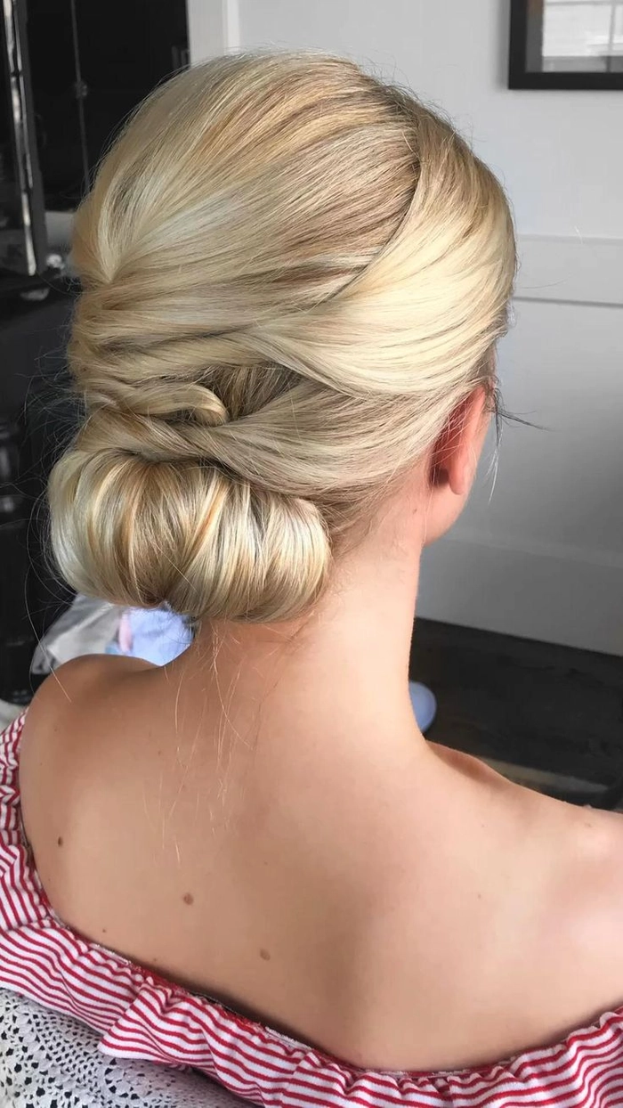 Chic and timeless wedding hairstyle featuring a twisted low bun Elegant wedding hair twisted low bun with delicate floral accents