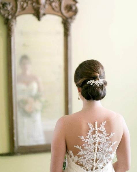 Wedding hair for backless dress showcasing a graceful updo with soft curls and floral accents Elegant wedding hairstyle perfectly styled for a backless dress with delicate accessories