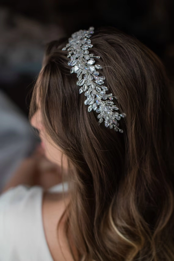 Romantic bridal look with a sparkling crystal tiara in styled hair Elegant wedding hairstyle featuring a crystal tiara enhancing soft curls
