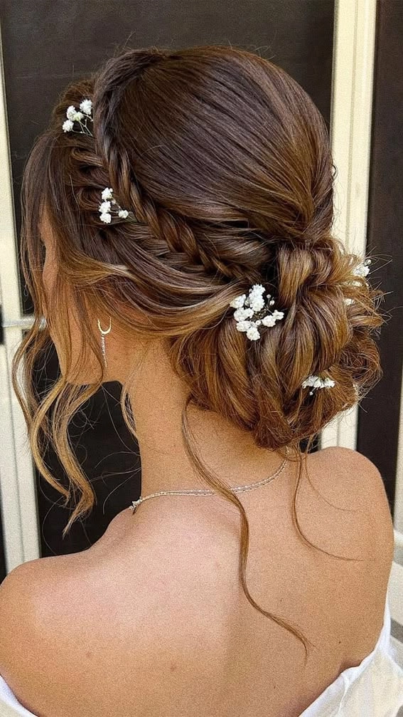Wedding hairstyle inspiration featuring a chic twisted low bun design Elegant wedding hair twisted low bun with delicate floral accents