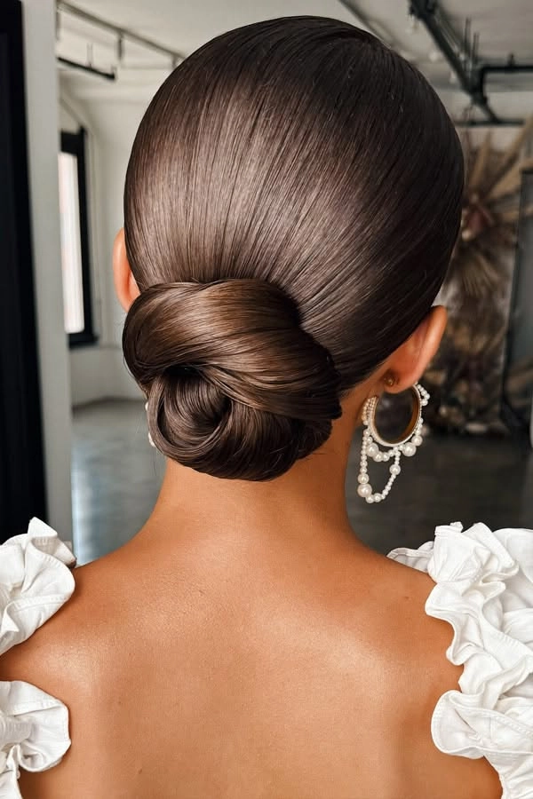 Classic low bun hairstyle with twisted details perfect for weddings Elegant wedding hair twisted low bun with delicate floral accessories