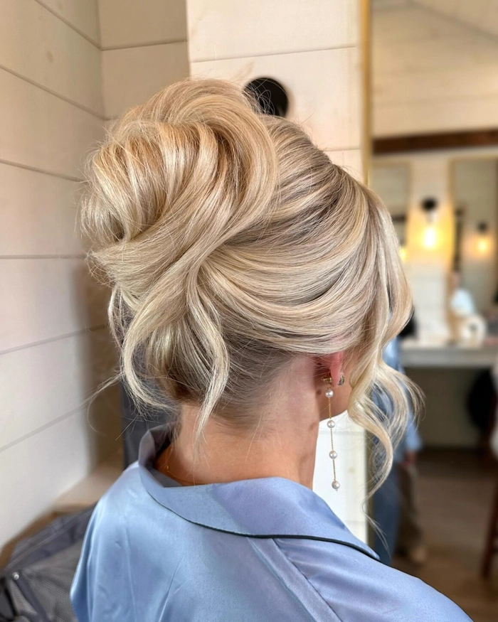 Elegant low bridal updo featuring textured waves and a relaxed finish Messy textured low bridal updo hairstyle with soft curls and tendrils