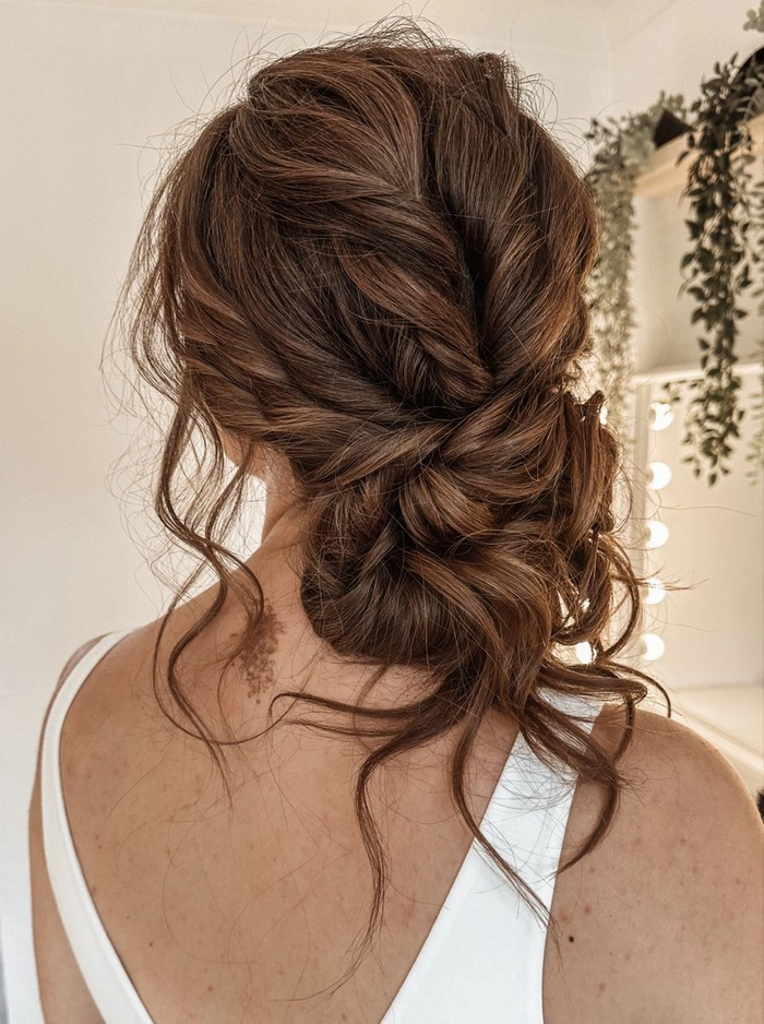 Elegant wedding hairstyle featuring a loose, textured low updo perfect for brides Messy textured low bridal updo hairstyle with soft curls and volume