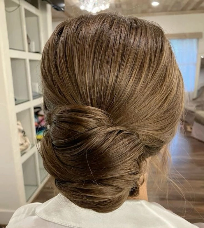 Elegant and effortless messy low updo hairstyle perfect for brides on their special day Messy textured low bridal updo with loose curls and soft tendrils for a romantic wedding look
