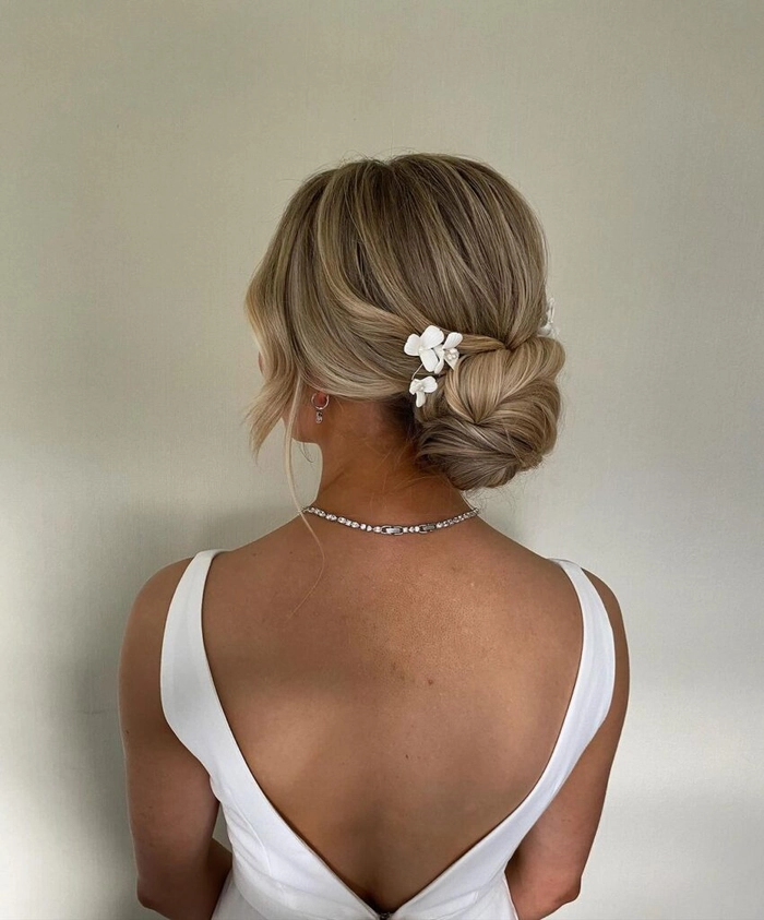Elegant modern minimalist bridal bun perfect for contemporary wedding hairstyles Bride wearing a modern minimalist bridal bun hairstyle with delicate floral accents