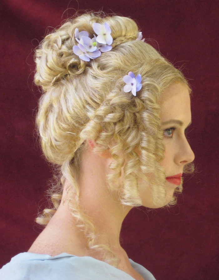 Victorian era inspired bridal hair styled with intricate curls and delicate floral accents