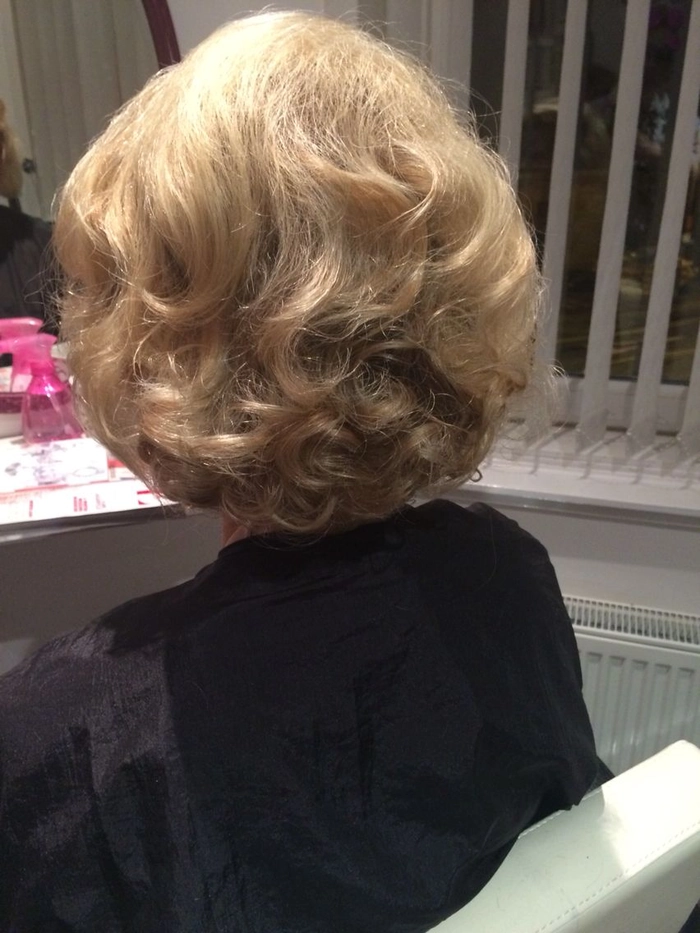 A mature businesswoman with a classic roller set hairstyle, looking professional and polished