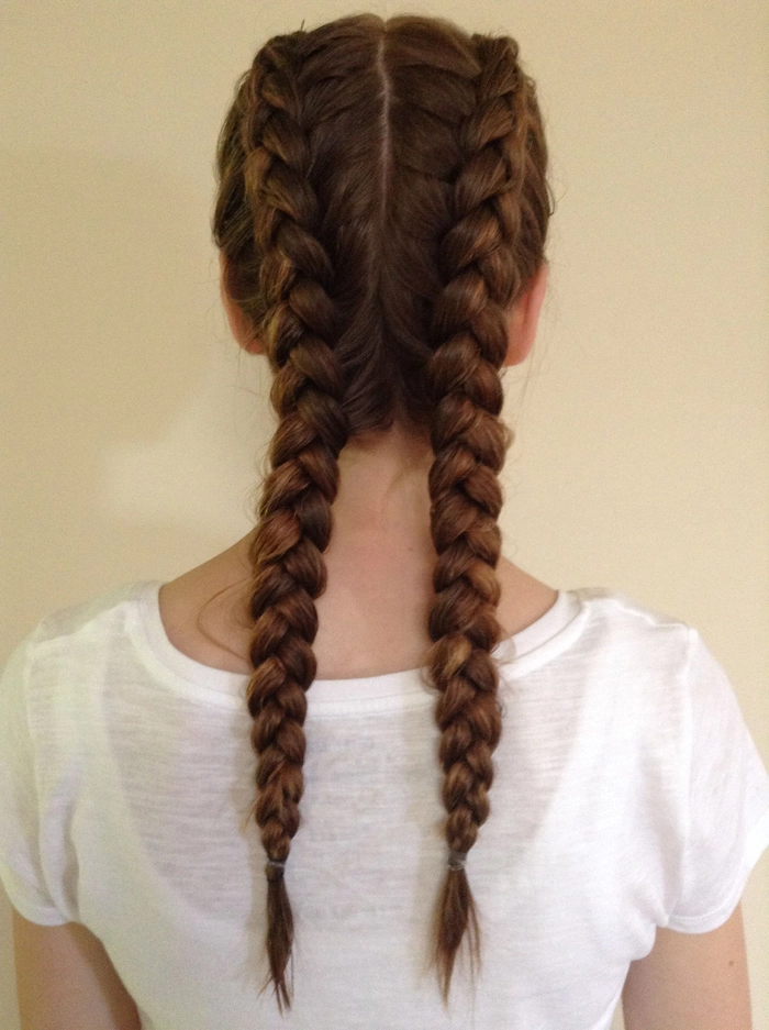Woman in business casual attire with double dutch braids actively working at a standing desk in a modern office