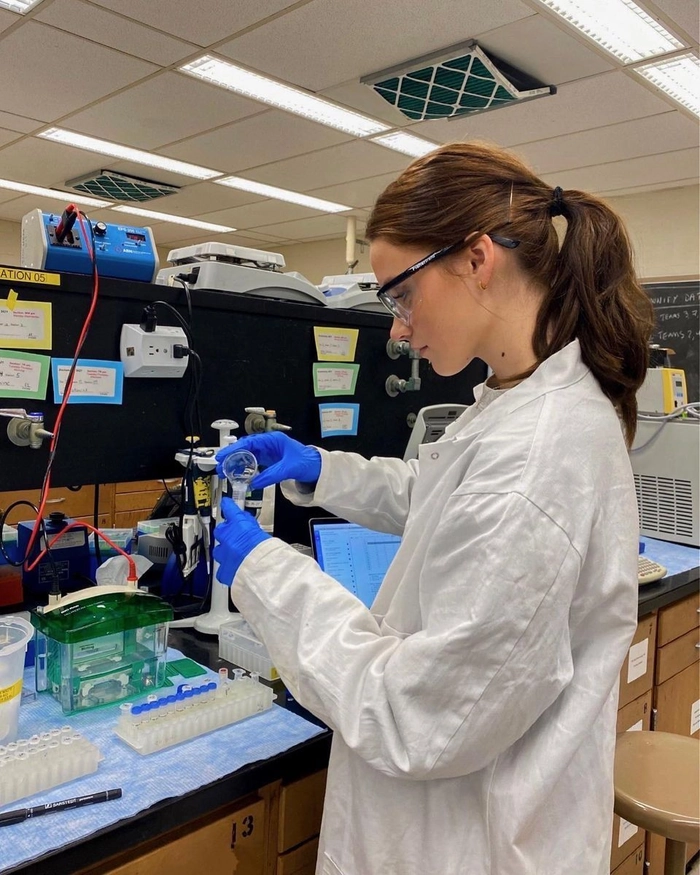 Laboratory technician wearing a bouffant cap over a low bun for complete hair containment