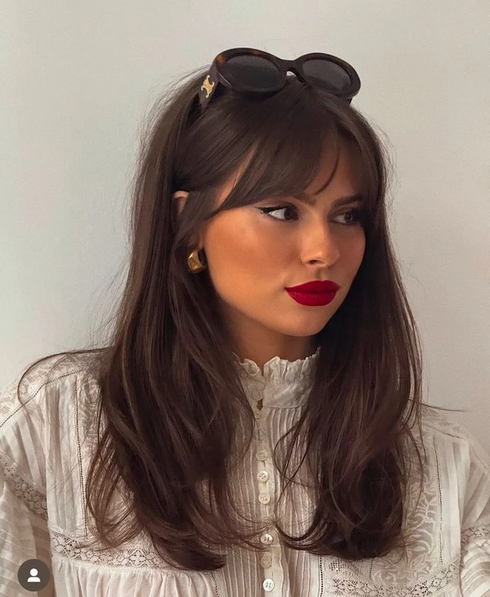 A professional woman with a forehead-covering fringe styled in sleek waves for the workplace