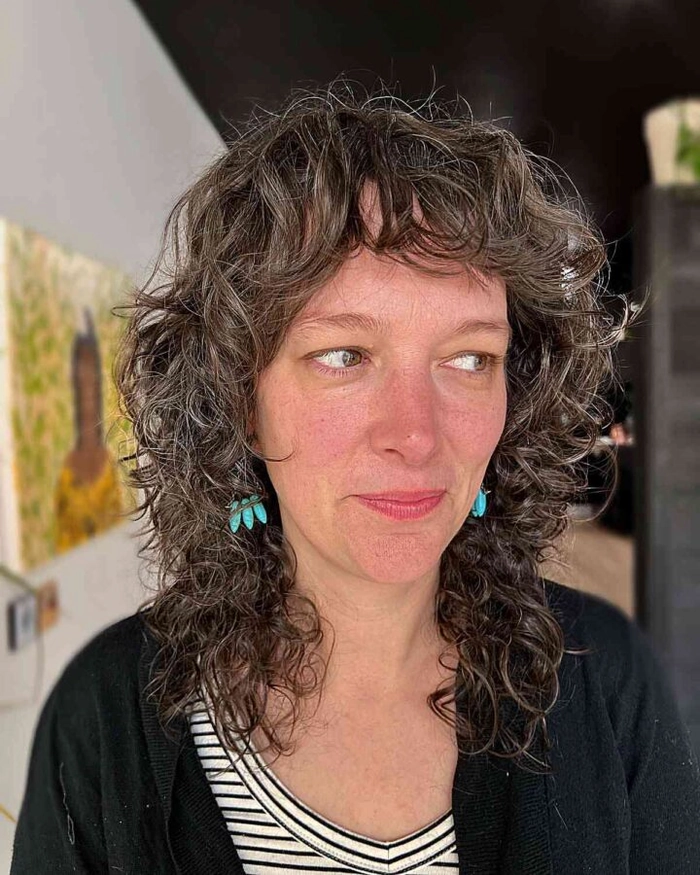 A creative professional over forty with a modern shag hairstyle, styled with subtle layers and soft waves for a professional yet artistic look