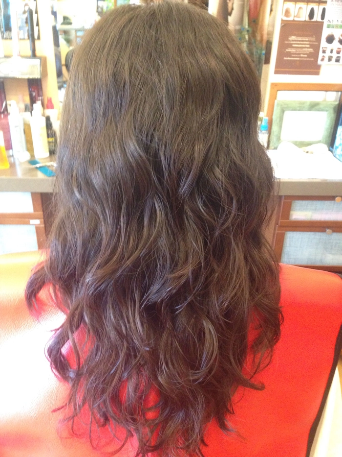 Professional woman at a desk with wavy hair secured in a low bun using a spiral hairpin.