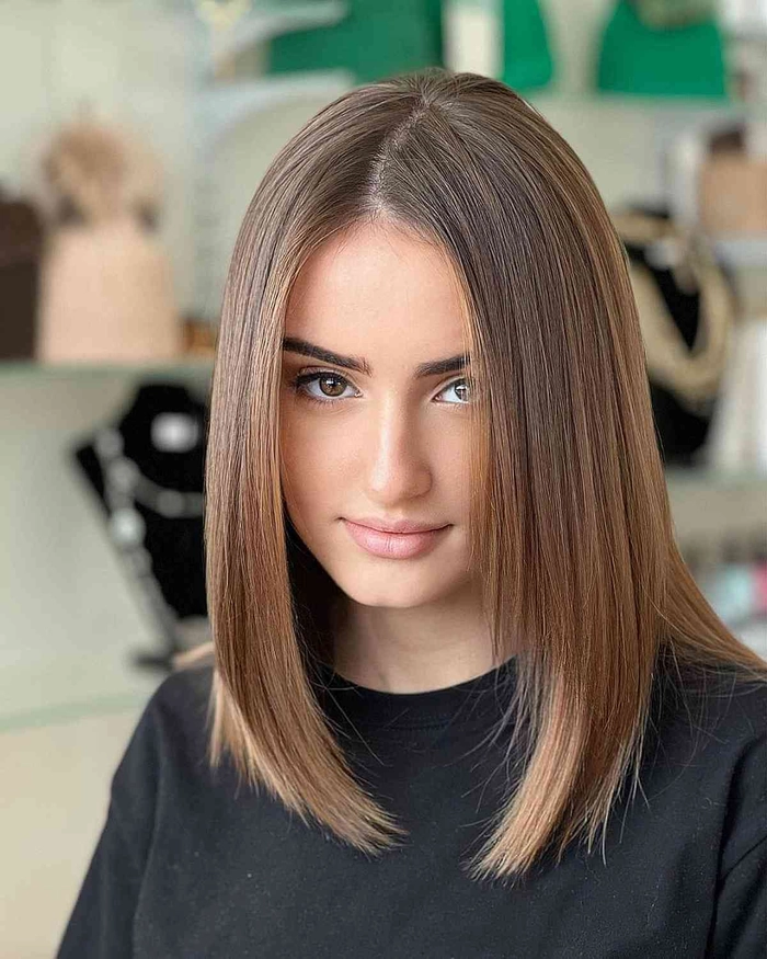 Tips for maintaining a straightened bob hairstyle throughout a nine-to-five workday A professional woman adjusting her sleek straightened bob hairstyle at her office desk during a work break