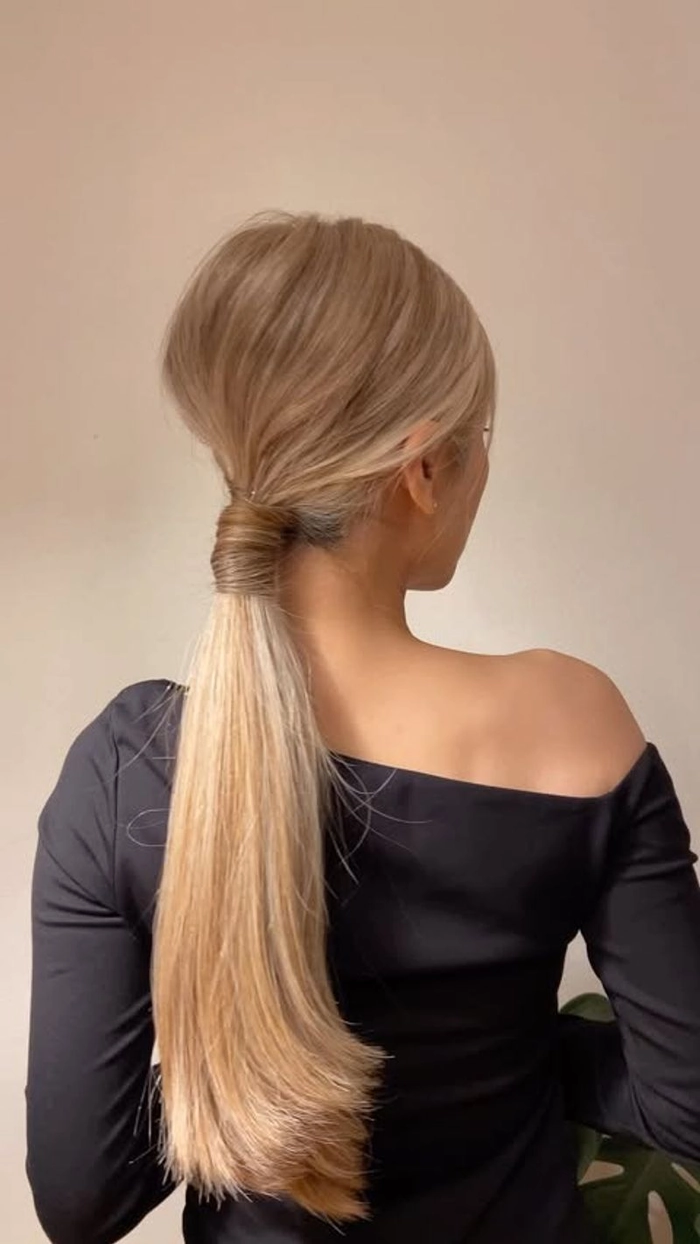 Woman with a knotted low ponytail hairstyle, neat and suitable for minimalist office aesthetics