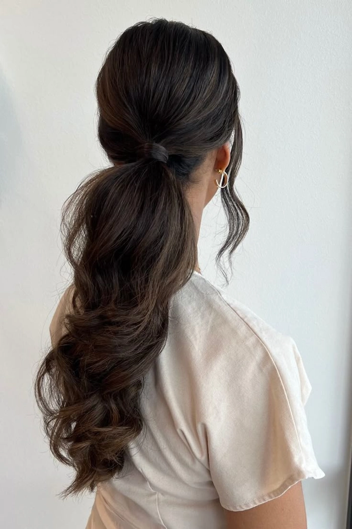 Woman wearing a sleek knotted low ponytail in a minimalist office outfit
