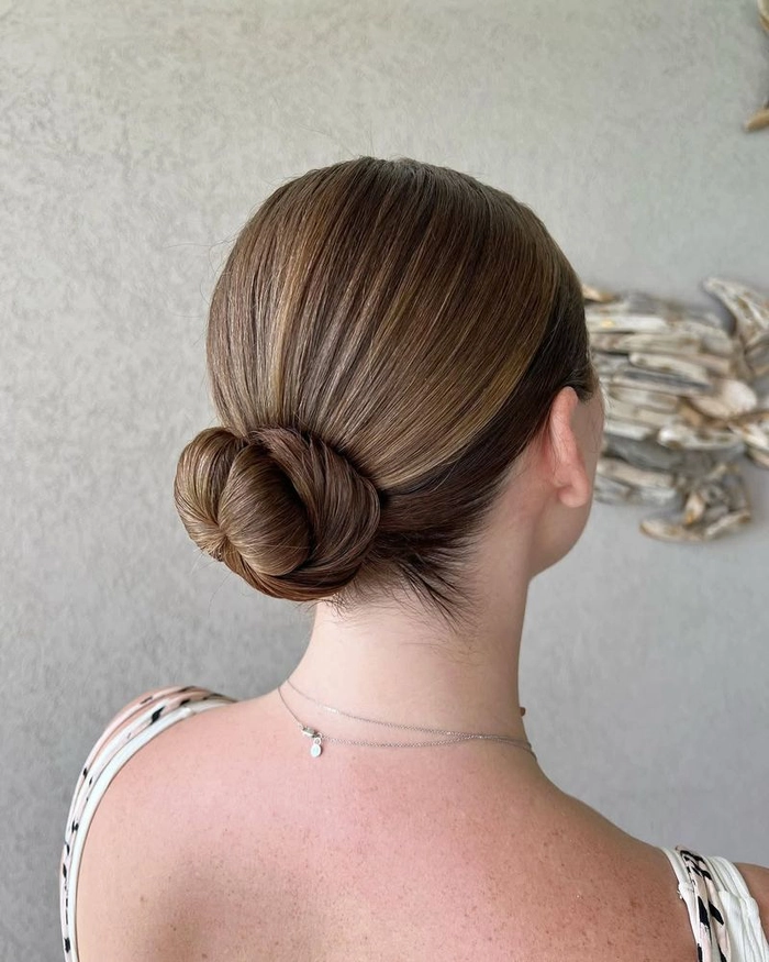 Close-up of minimalist hairpin placements securing a sleek office bun from behind