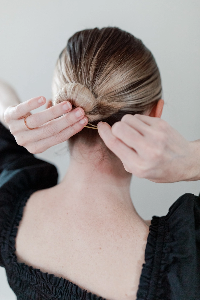Minimalist hairpin placement creating a sleek low office bun