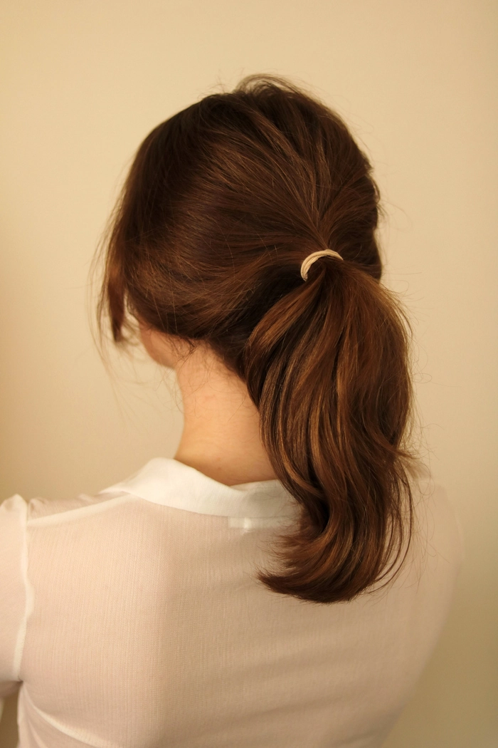 A sleek low ponytail with side-swept hair for a professional client meeting look