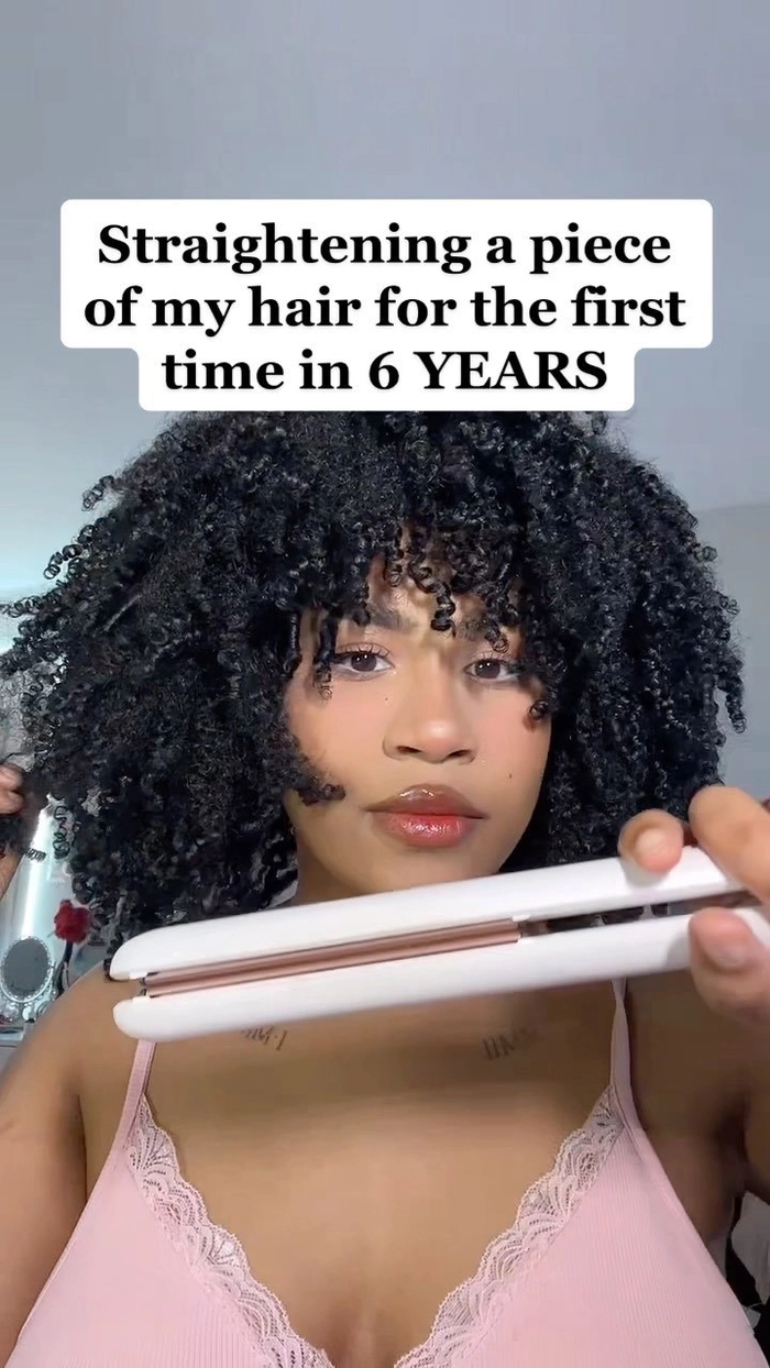 A professional woman with naturally curly hair styled into a sleek, smooth blowout perfect for the office.