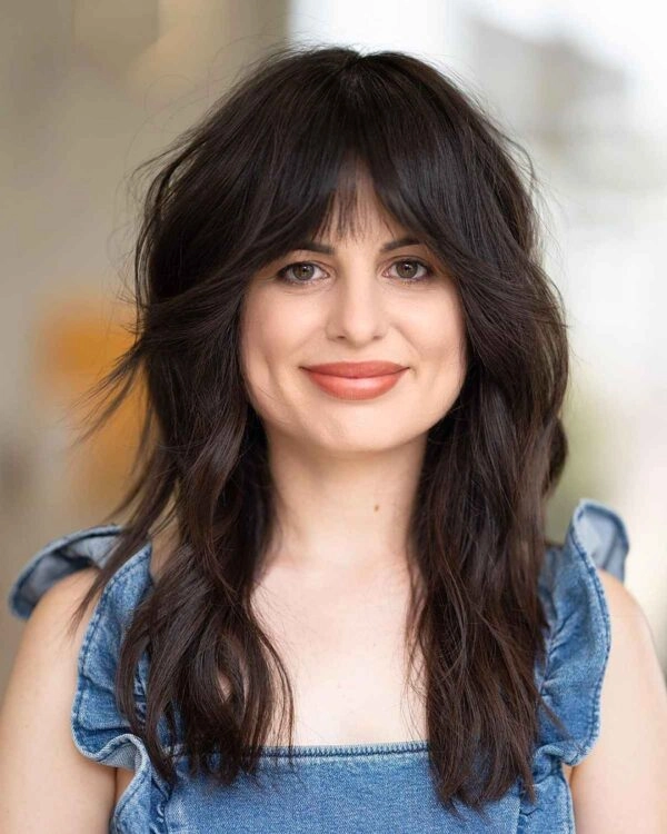 Professional woman with square face wearing soft, wispy bangs that flatter her features in a corporate office setting