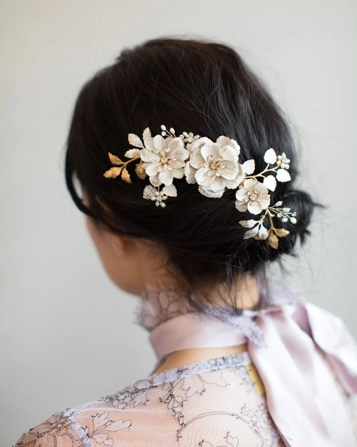 A woman with a loose low ponytail adorned with a small floral clip, blending spring style into a relaxed office look