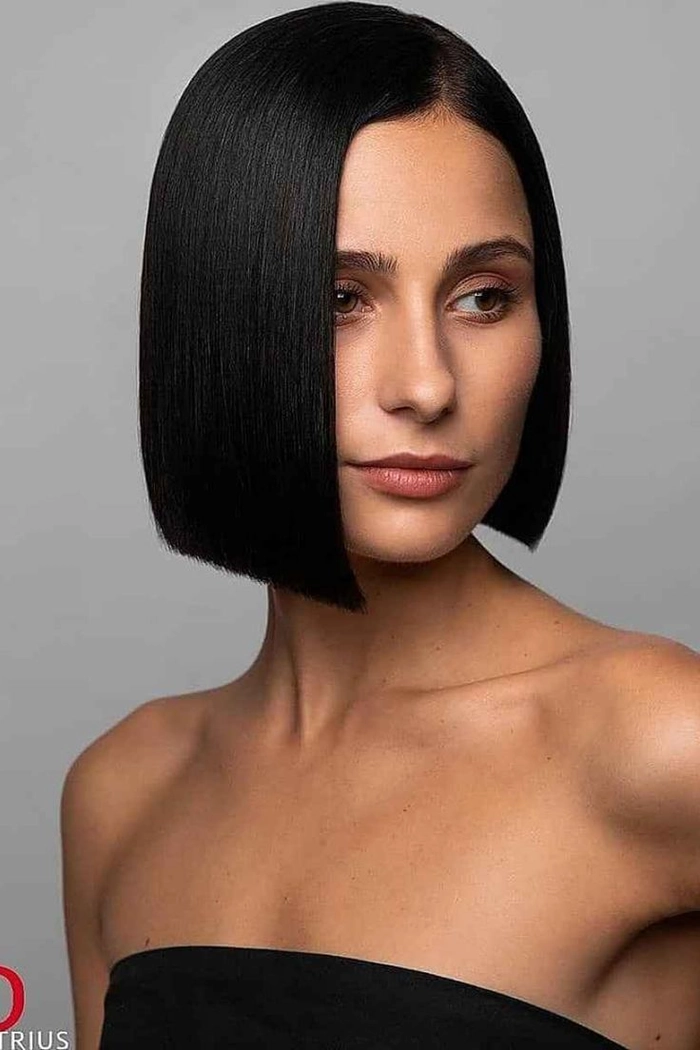 Straightened bob maintenance tips for the nine to five workday Woman touching her sleek straightened bob hairstyle in a professional office setting, ready for a work shift