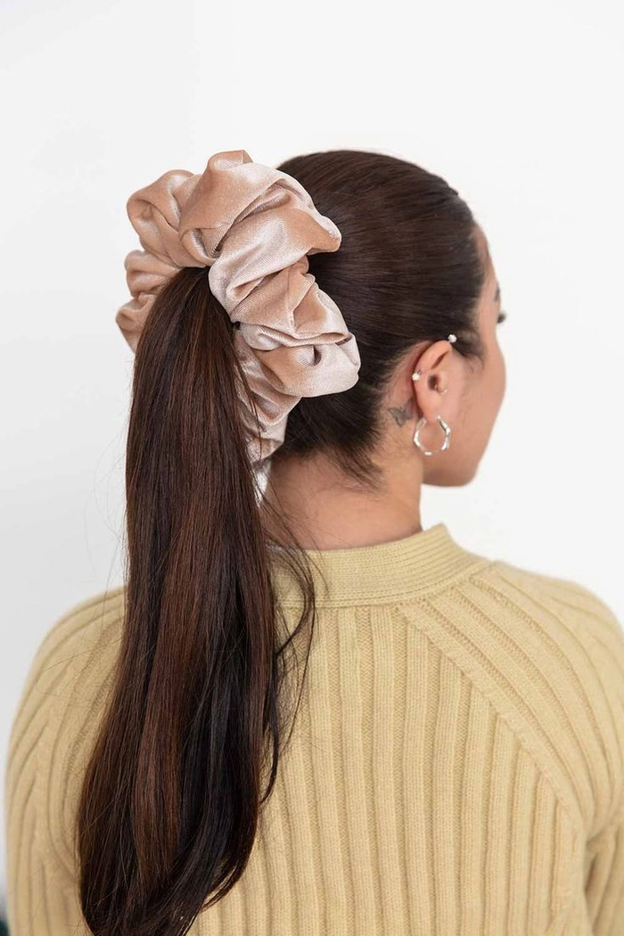 Velvet scrunchie styling for a polished business casual ponytail at work A professional woman wearing a velvet scrunchie in a sleek low ponytail for a business casual office look