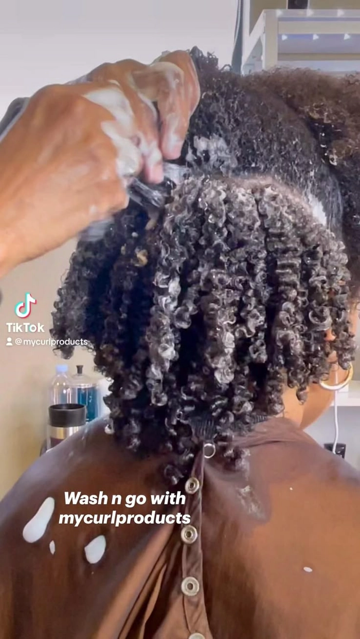Professional woman with defined natural curls in a polished wash and go style, suitable for office wear