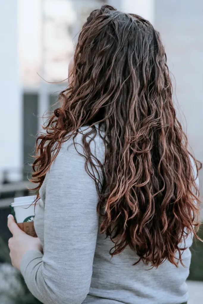 Woman with wavy hair pinned in a low twist bun while typing at a desk