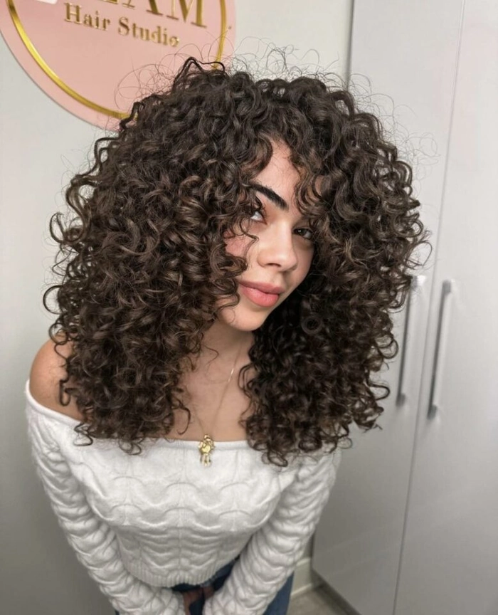 Wavy hair contained in a low bun with a silk scarf to reduce frizz at a desk job