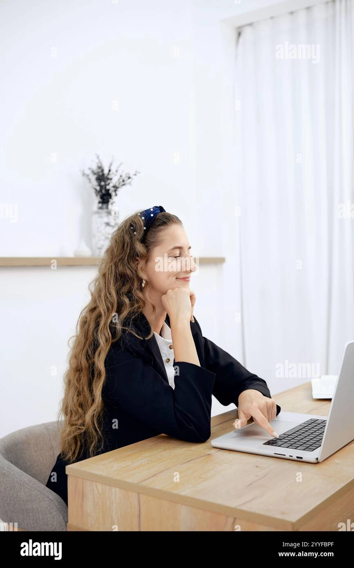 Woman with wavy hair secured in a low bun while working at a computer